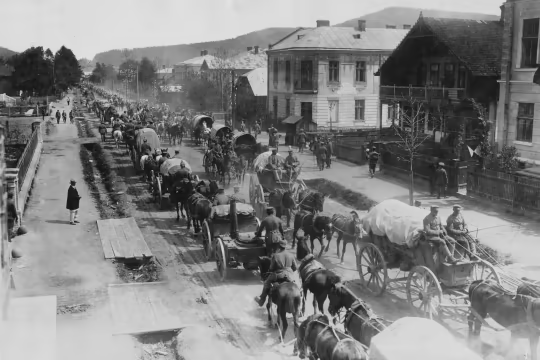 A black and white photo dated c1915 of military vehicles passing through a town